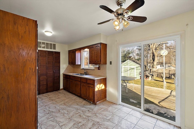 kitchen featuring visible vents, a sink, light tile patterned flooring, light countertops, and ceiling fan