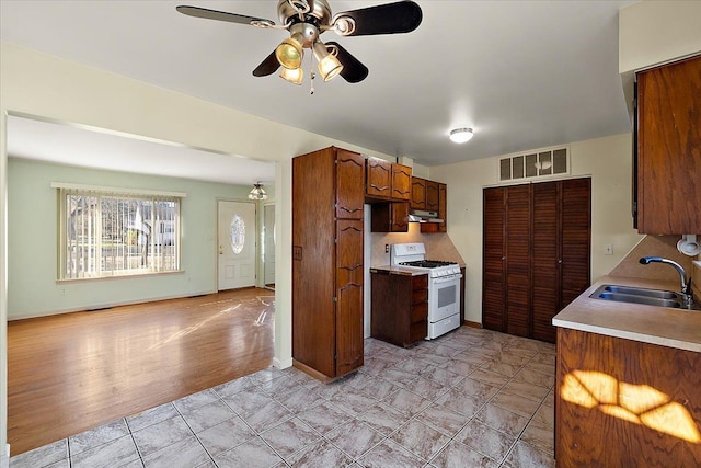 kitchen with visible vents, a sink, white gas range oven, light countertops, and ceiling fan