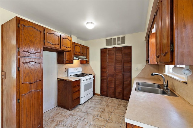 kitchen with visible vents, white range with gas cooktop, a sink, under cabinet range hood, and light countertops