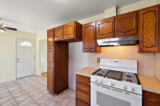 kitchen featuring under cabinet range hood, a ceiling fan, light countertops, and gas range gas stove