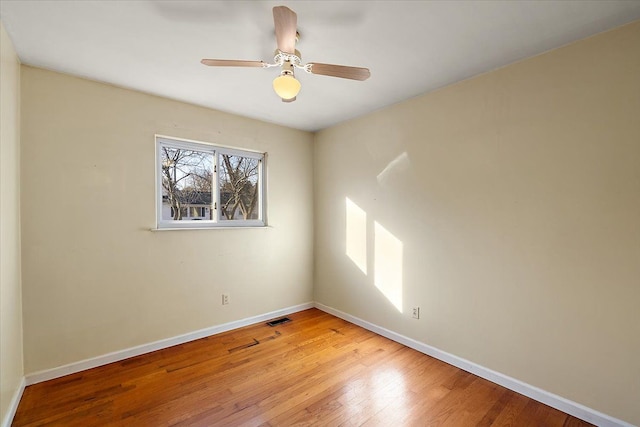 empty room featuring light wood-type flooring, visible vents, baseboards, and ceiling fan