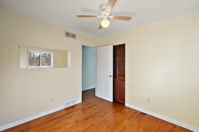 unfurnished room featuring visible vents, baseboards, hardwood / wood-style floors, and a ceiling fan