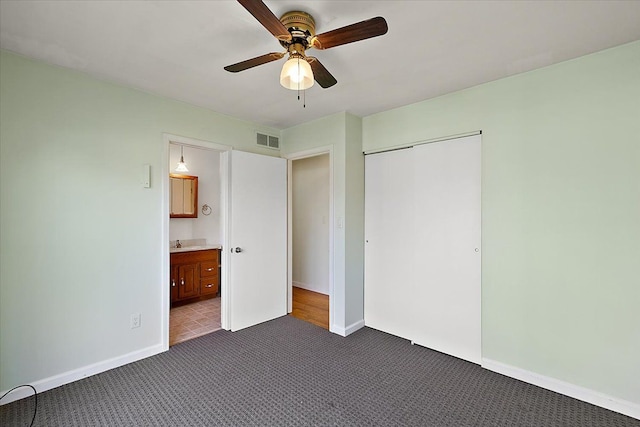 unfurnished bedroom with a closet, baseboards, visible vents, and dark carpet