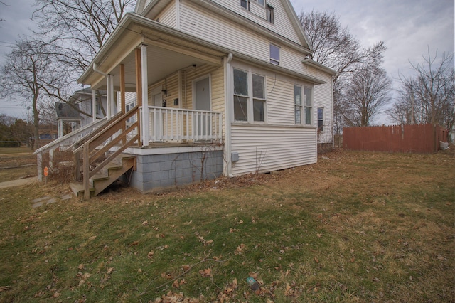 view of home's exterior with a porch, a lawn, and fence