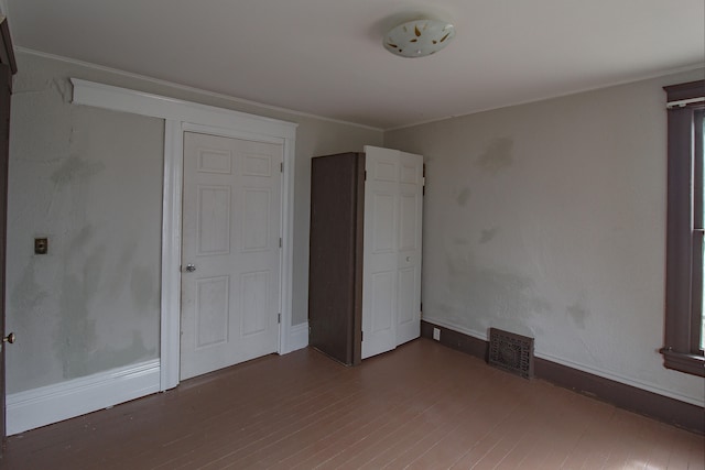 unfurnished bedroom featuring baseboards, visible vents, and wood finished floors