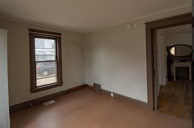 spare room featuring wood-type flooring, a fireplace, visible vents, and baseboards