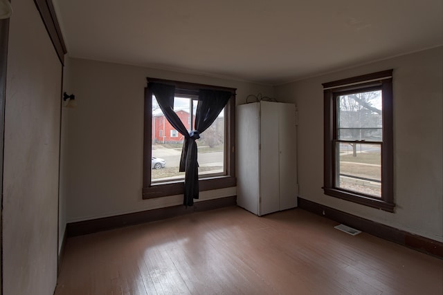 spare room featuring baseboards, visible vents, and hardwood / wood-style floors