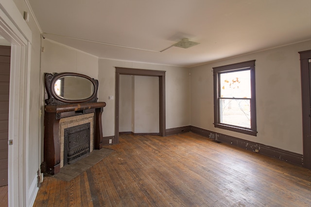 unfurnished living room with baseboards, a tile fireplace, hardwood / wood-style flooring, and crown molding