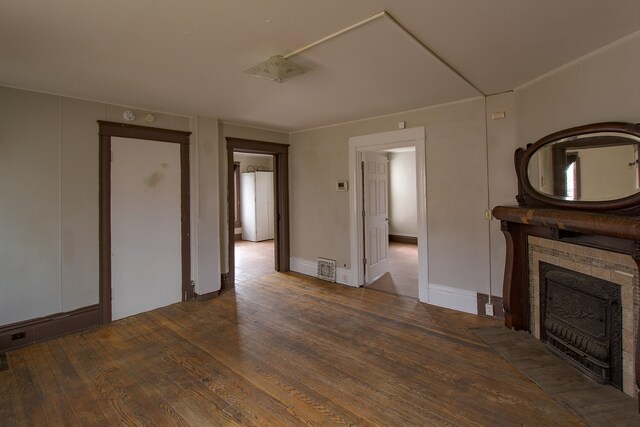 unfurnished living room with a tile fireplace, visible vents, baseboards, and hardwood / wood-style flooring