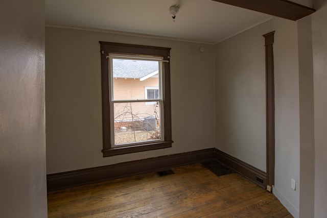 empty room with ornamental molding, hardwood / wood-style floors, visible vents, and baseboards