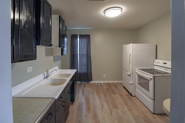 kitchen featuring dark cabinets, white appliances, visible vents, light countertops, and light wood-type flooring