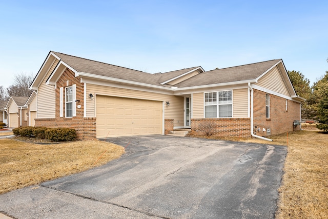 ranch-style house featuring a garage, driveway, brick siding, and a front yard