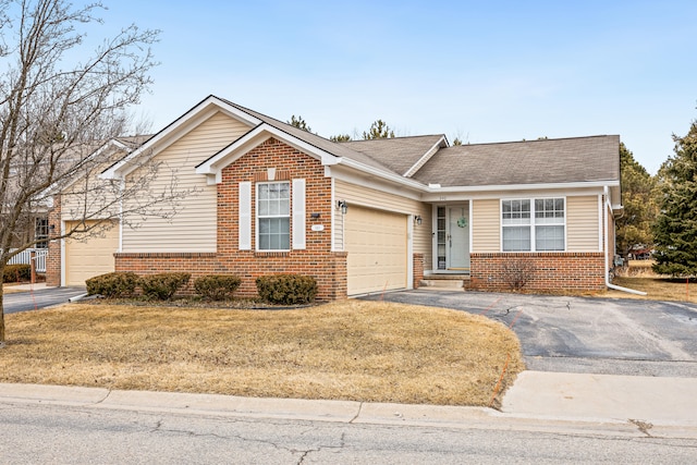 view of front of home with driveway, an attached garage, a front yard, and brick siding