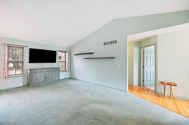 unfurnished living room with lofted ceiling, carpet floors, and visible vents