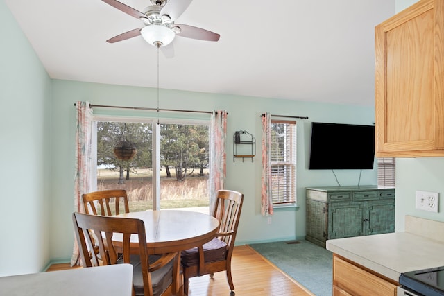 dining space featuring ceiling fan, light wood finished floors, and baseboards