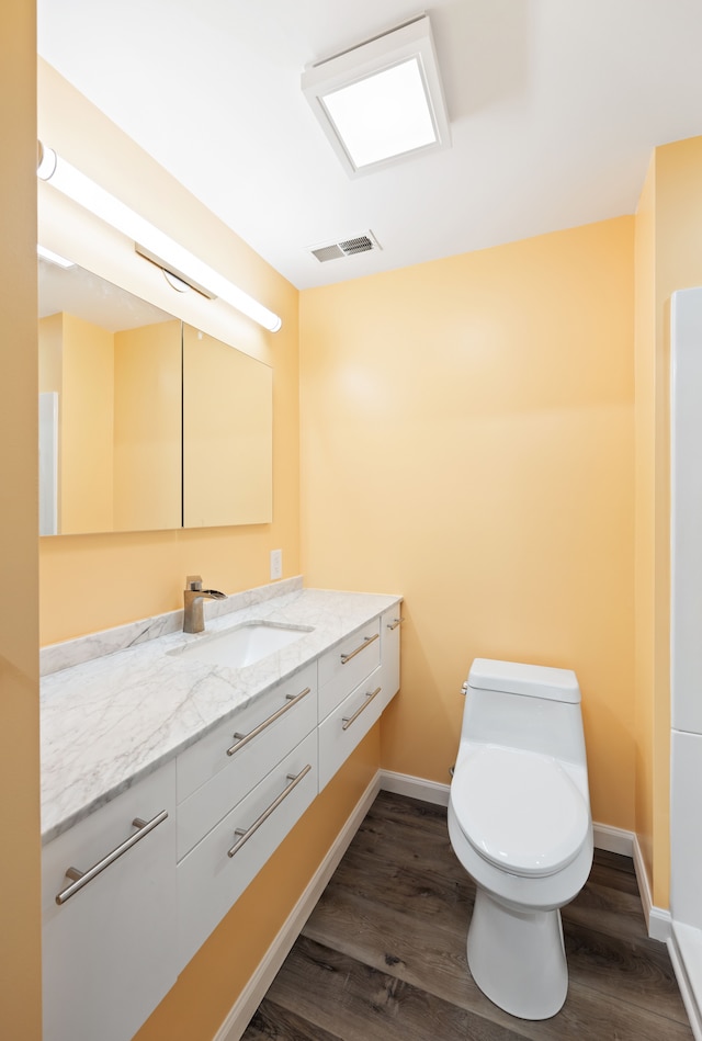 bathroom featuring baseboards, visible vents, toilet, and wood finished floors