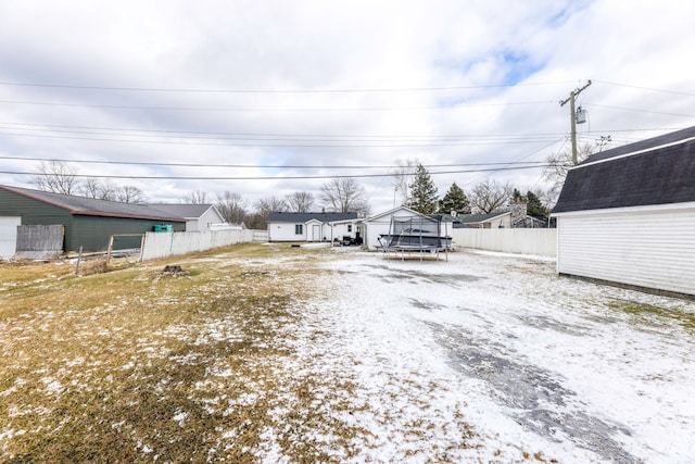 view of yard with a trampoline, an outbuilding, and fence