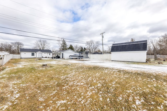 view of yard featuring a storage unit, a trampoline, an outdoor structure, and fence