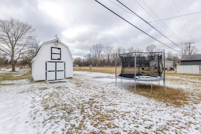 yard covered in snow with a trampoline, an outbuilding, and a barn