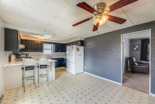 kitchen featuring a peninsula, under cabinet range hood, white fridge with ice dispenser, and light countertops