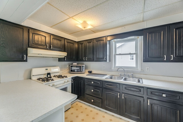 kitchen with light floors, stainless steel microwave, a sink, white range with gas cooktop, and under cabinet range hood