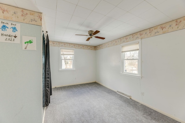 spare room featuring carpet floors, visible vents, baseboards, and a ceiling fan