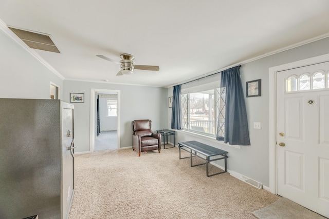 entrance foyer with carpet floors, a ceiling fan, baseboards, and crown molding