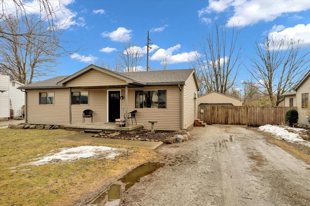 view of front of property with driveway, a shingled roof, and fence