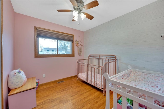 bedroom featuring light wood finished floors, a ceiling fan, visible vents, and baseboards