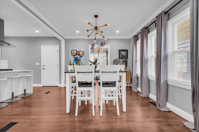 dining space featuring a chandelier, wood finished floors, baseboards, and ornamental molding