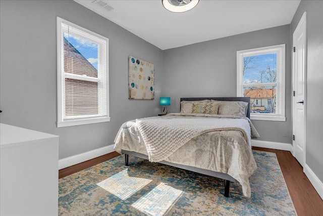 bedroom featuring visible vents, baseboards, and wood finished floors