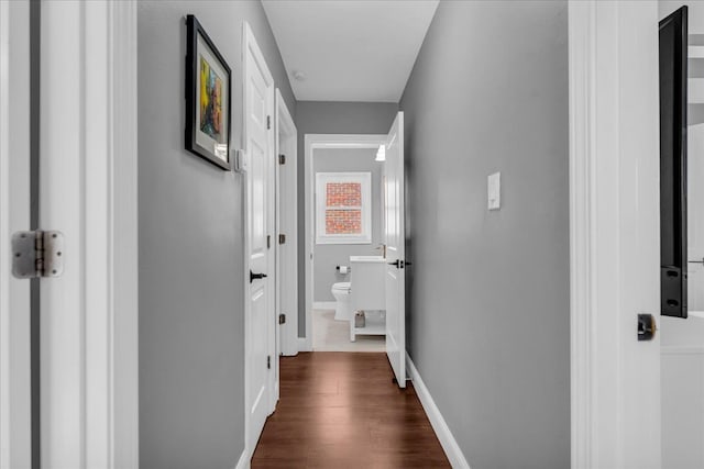 corridor with dark wood finished floors and baseboards