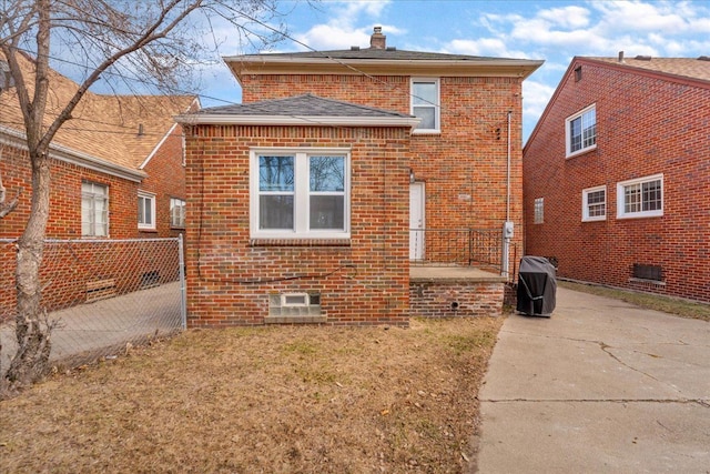 back of property with brick siding, a chimney, a yard, and fence