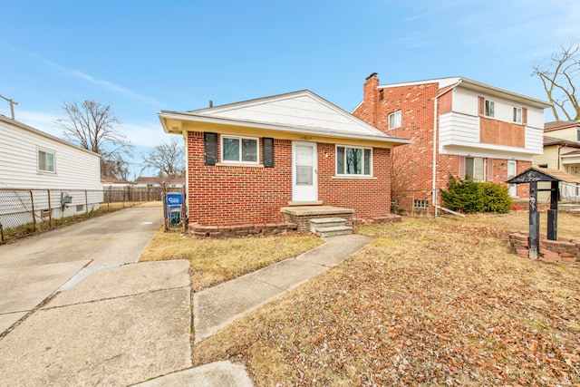 view of front of home with driveway, fence, and brick siding