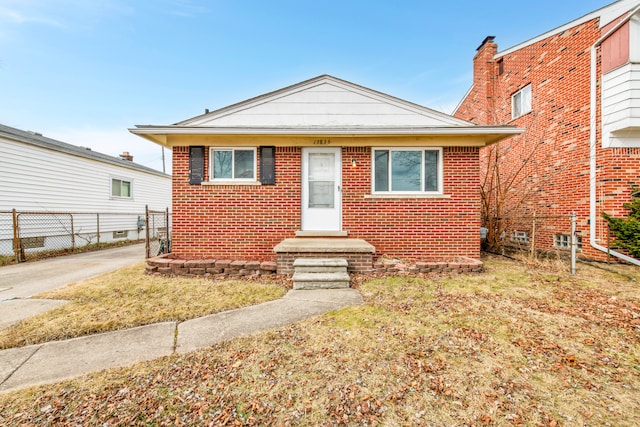 bungalow-style home featuring brick siding and fence