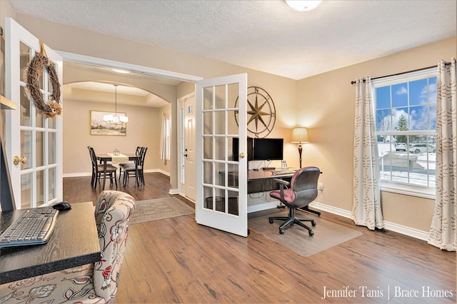 office space featuring arched walkways, french doors, baseboards, and wood finished floors