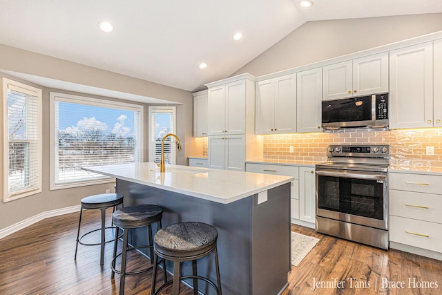 kitchen featuring appliances with stainless steel finishes, lofted ceiling, light countertops, and a sink