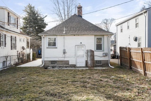 back of property featuring a yard, roof with shingles, fence, and a chimney