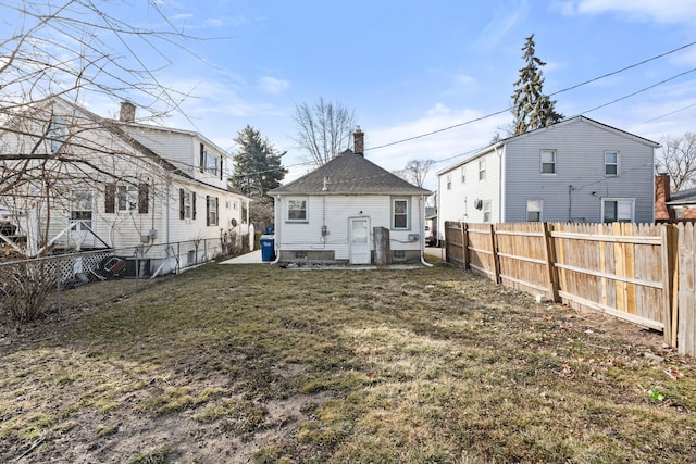 rear view of property featuring a fenced backyard and a lawn