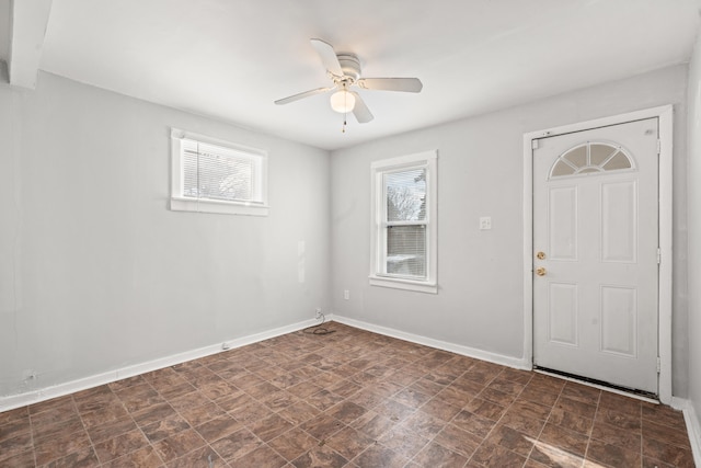 foyer featuring a ceiling fan, plenty of natural light, and baseboards