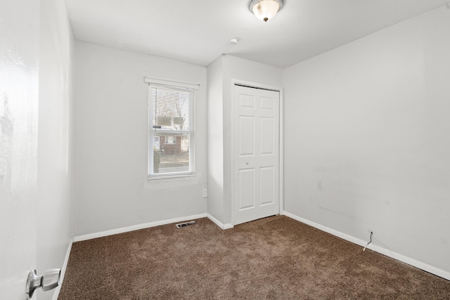 spare room featuring carpet, visible vents, and baseboards