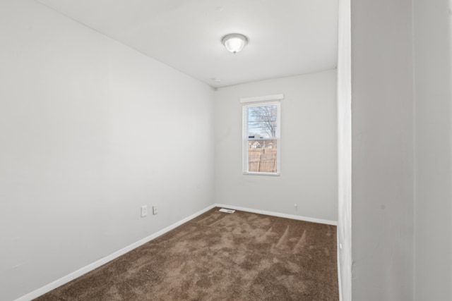 empty room with dark colored carpet and baseboards