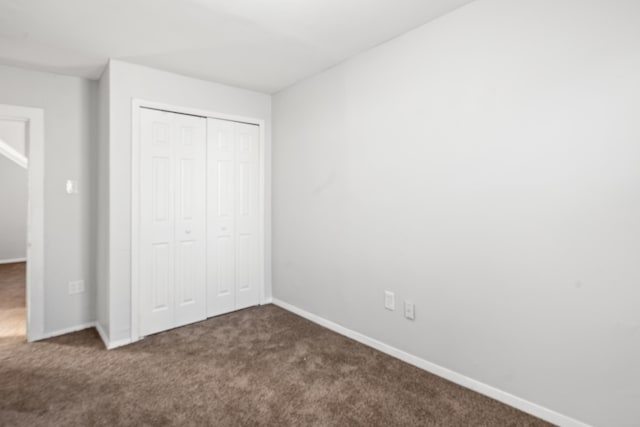 unfurnished bedroom with a closet, carpet flooring, and baseboards