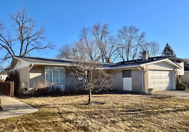 view of front of property with driveway, a front yard, a garage, brick siding, and a chimney