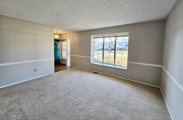 carpeted spare room featuring visible vents, a textured ceiling, and baseboards