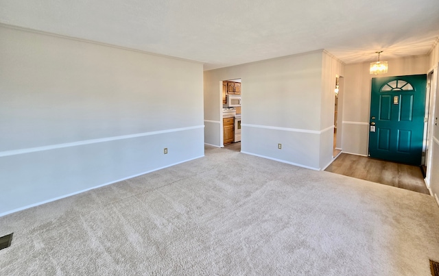 foyer entrance featuring a notable chandelier, carpet flooring, and baseboards