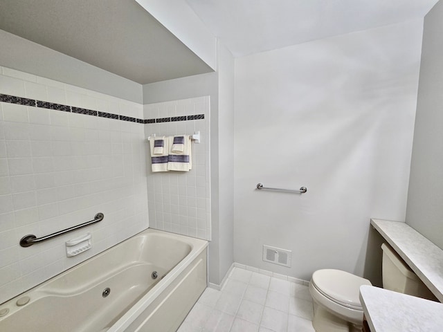 bathroom featuring toilet, a combined bath / shower with jetted tub, tile patterned flooring, baseboards, and vanity