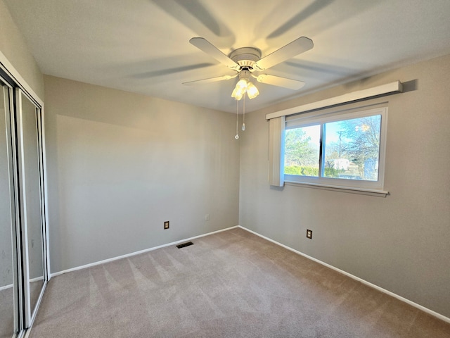 carpeted spare room with visible vents, ceiling fan, and baseboards