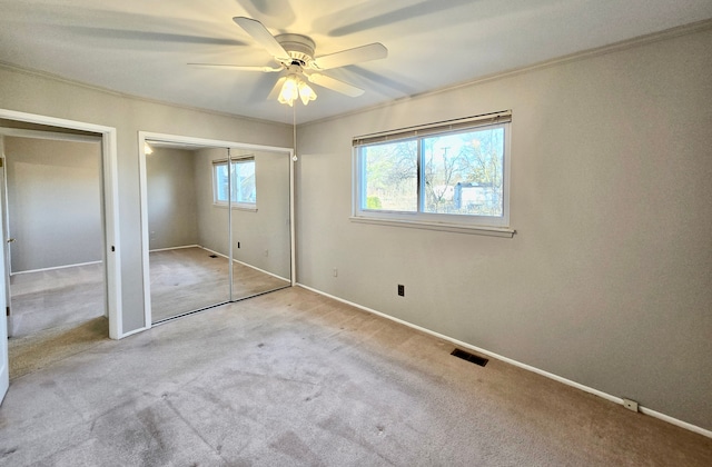 unfurnished bedroom featuring carpet flooring, two closets, visible vents, and ornamental molding