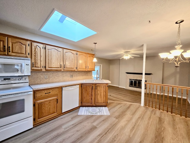 kitchen with light wood-type flooring, a sink, a glass covered fireplace, white appliances, and light countertops